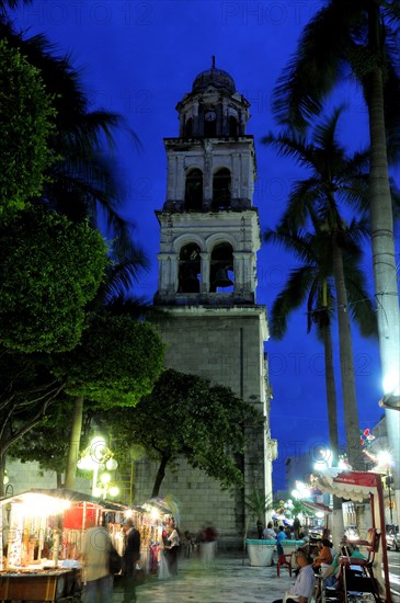Mexico, Veracruz, Stalls in the Zocalo with the cathedral bell tower behind at night with illuminated street lights. Photo : Nick Bonetti
