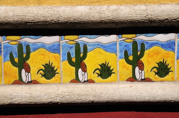 Mexico, Bajio, San Miguel de Allende, Detail of colourful tile depicting figure in Mexican hat sitting at foot of cactus. Photo : Nick Bonetti
