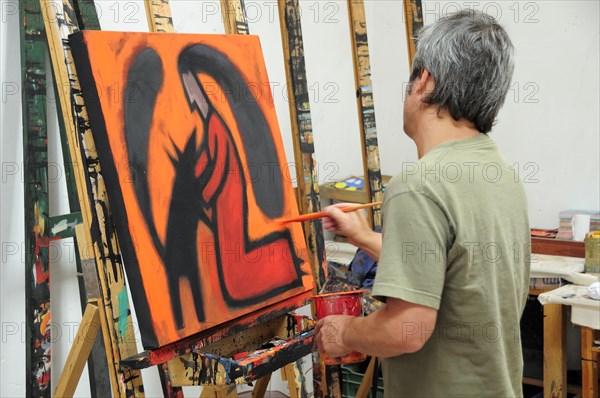 Mexico, Bajio, San Miguel de Allende, Artist Juan Ezcurdia in his studio working on painting at easel. Photo : Nick Bonetti