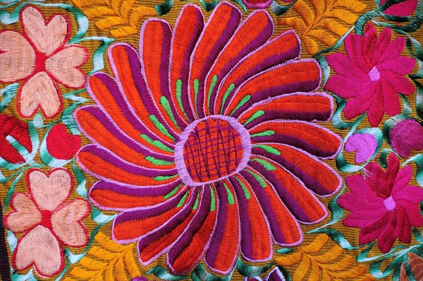 Mexico, Bajio, San Miguel de Allende, Detail of brightly embroidered textile in arts shop with flower design in pink red and orange. Photo : Nick Bonetti