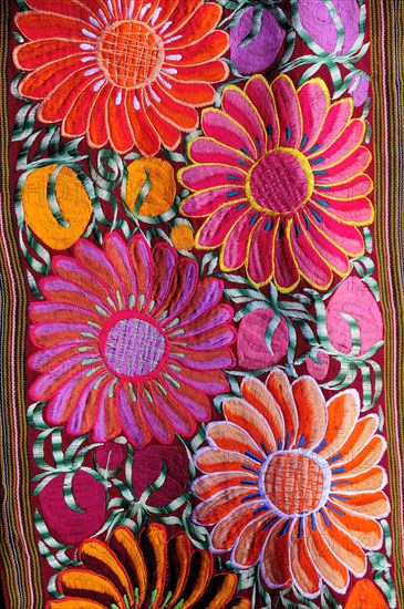 Mexico, Bajio, San Miguel de Allende, Detail of brightly coloured embroidered textile in arts shop with flower design in pink red and orange. Photo : Nick Bonetti