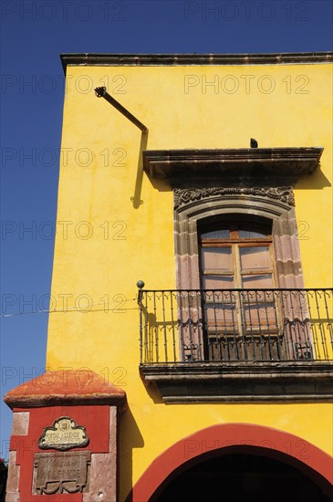 Mexico, Bajio, San Miguel de Allende, El Jardin Part view of yellow painted exterior facade of building with French windows and balcony. Photo : Nick Bonetti