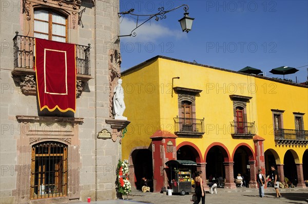 Mexico, Bajio, San Miguel de Allende, El Jardin Part view of Museo Casa de Allende and yellow painted arcades people and fruit juice vendor. Photo : Nick Bonetti