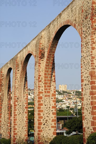 Mexico, The Bajio, Queretaro, Aquaduct arches framing view towards city buildings on hillside beyond.. Photo : Nick Bonetti