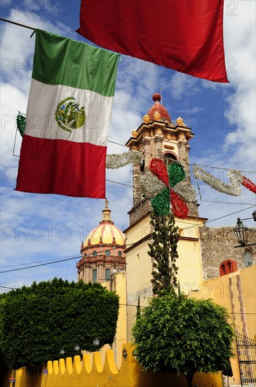 Mexico, Bajio, San Miguel de Allende, Mexican flags and Independence Day decorations hang in foreground of church. Photo : Nick Bonetti