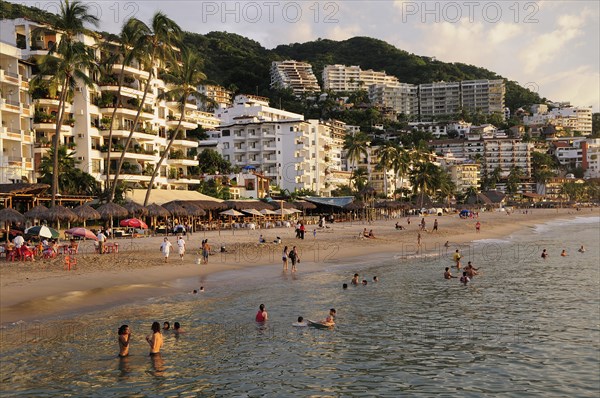 Mexico, Jalisco, Puerto Vallarta, View of Playa Los Muertos beach overlooked by hotels and apartments and lined with bars cafes and beach shades. People on beach and in the water. Photo : Nick Bonetti