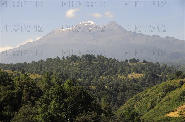Mexico, Puebla, View of Ixtaccihuatl volcano with wooded parkland in foreground. Photo : Nick Bonetti