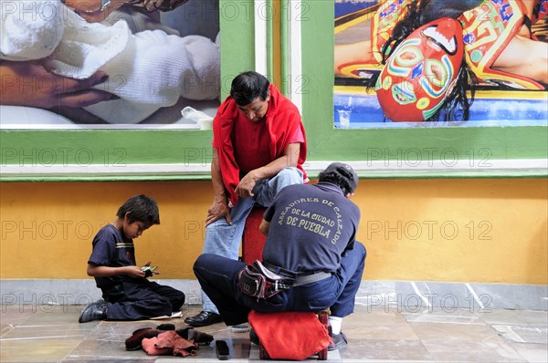 Mexico, Puebla, Shoeshine stand in front of posters. Photo : Nick Bonetti