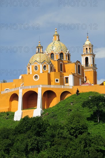 Mexico, Puebla, Cholula, Church of Neustra Senor de los Remedios or Our Lady of Remedios on wooded hillside above the pyramid ruins with brightly painted exterior in neoclassical style.. Photo : Nick Bonetti