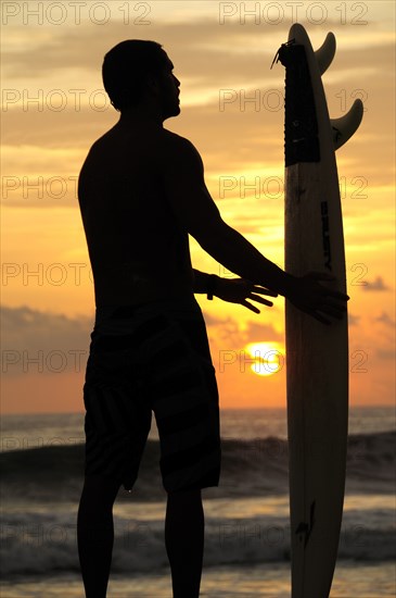 Mexico, Oaxaca, Puerto Escondido, Surfer and board silhouetted at sunset on Playa Zicatela. Photo : Nick Bonetti