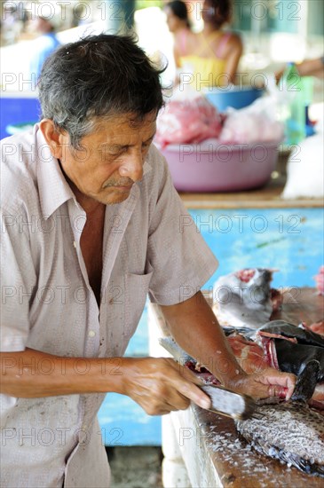 Mexico, Oaxaca, Puerto Escondido, Playa Principal Man preparing fresh fish in the market.. Photo : Nick Bonetti