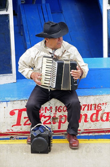 Mexico, Michoacan, Patzcuaro, Lago Patzcuaro Musician playing the accordion sitting on painted boat.. Photo : Nick Bonetti