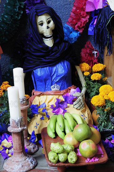 Mexico, Michoacan, Patzcuaro, Dia de los Muertos Day of the Dead altar with figures food candles and flowers. Photo : Nick Bonetti