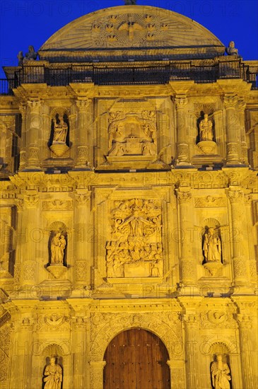 Mexico, Oaxaca, Part view of baroque exterior facade of cathedral at night with relief carving of the assumption of the Virgin Mary above door. Photo : Nick Bonetti
