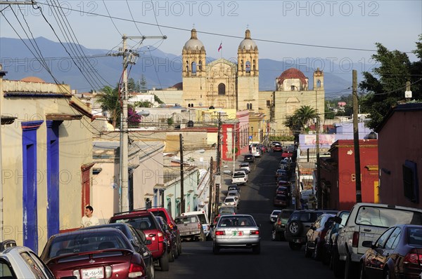 Mexico, Oaxaca, View along street lined by parked vehicles towards church of Santo Domingo. Photo : Nick Bonetti