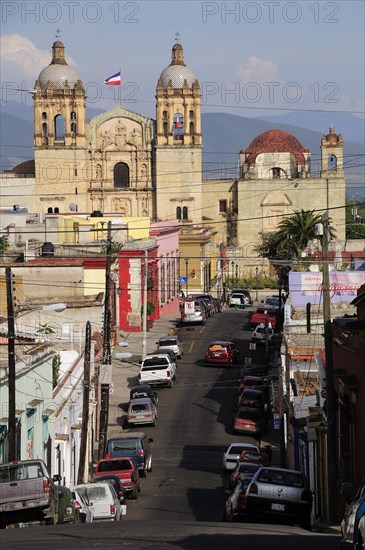 Mexico, Oaxaca, View along street lined with parked vehicles towards church of Santo Domingo. Photo : Nick Bonetti