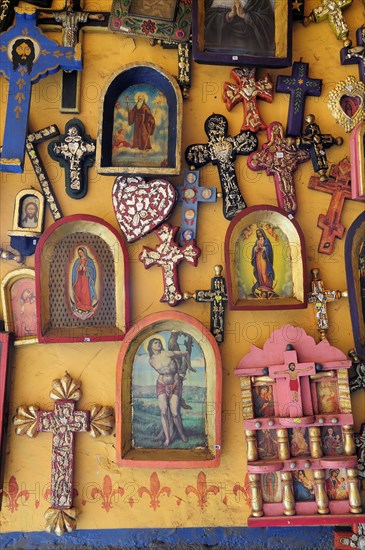 Mexico, Michoacan, Patzcuaro, Religious kitsch art displayed on yellow painted wall. Photo : Nick Bonetti