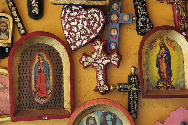 Mexico, Michoacan, Patzcuaro, Religious kitsch art displayed on yellow painted wall. Photo : Nick Bonetti