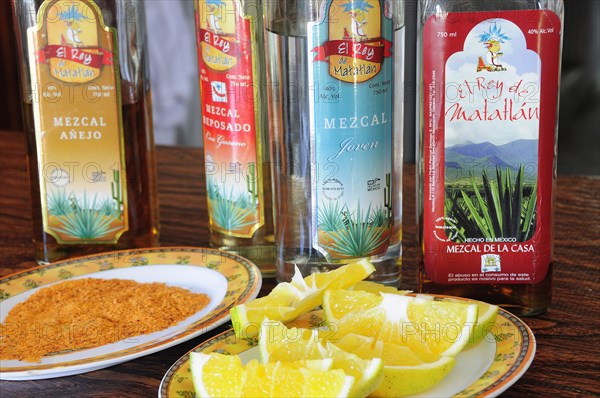 Mexico, Oaxaca, Bottles of Mezcal and slices of oranges. Photo : Nick Bonetti