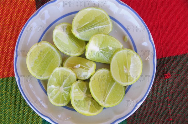 Mexico, Oaxaca, Huatulco, Blue and white bowl with cut halves of limes on red and green woven cloth. Photo : Nick Bonetti