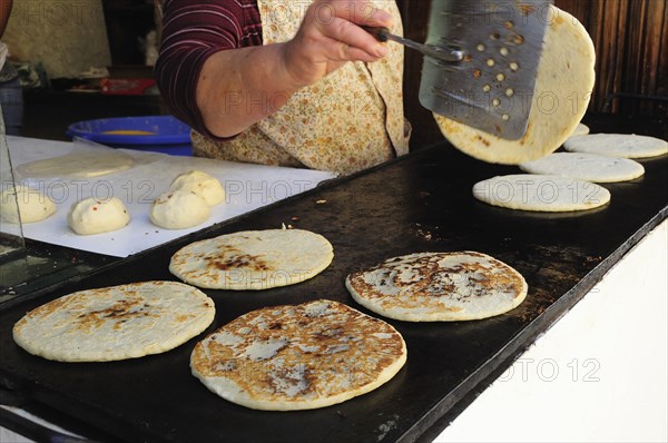 Mexico, Bajio, San Miguel de Allende, Cropped shot of woman making tortillas turning them as they cook on griddle.1. Photo : Nick Bonetti