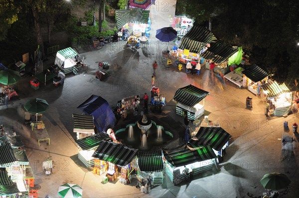 Mexico, Federal District, Mexico City, View onto Alameda park at night from Torre Latinoamericana with green and white striped roof awnings of street stalls below. Photo : Nick Bonetti