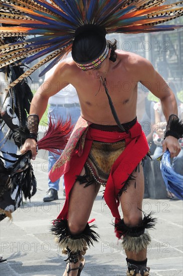 Mexico, Federal District, Mexico City, Michacoa Aztec dancer wearing brightly coloured feather head-dress performing in the Zocalo. Photo : Nick Bonetti