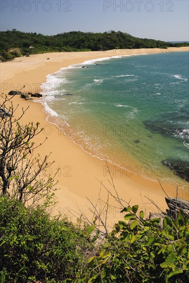 Mexico, Oaxaca, Huatulco, View onto deserted beach at Playa Conejos with turquoise water and golden sand. Photo : Nick Bonetti