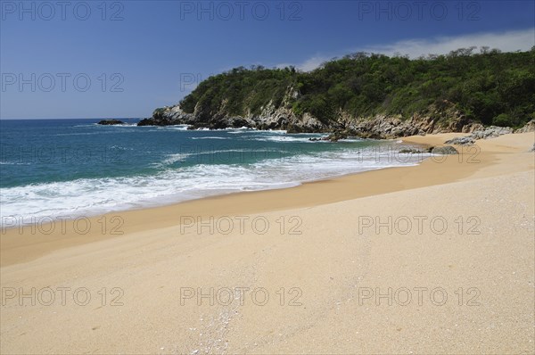 Mexico, Oaxaca, Huatulco, Playa Conejos Deserted beach with turquoise sea breaking on sandy shore and rocky headland. Photo : Nick Bonetti