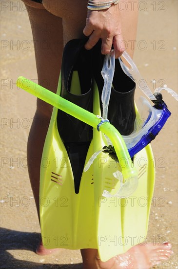 Mexico, Oaxaca, Huatulco, Playa La Entrega Cropped shot of woman snorkler carrying mask and flippers.. Photo : Nick Bonetti