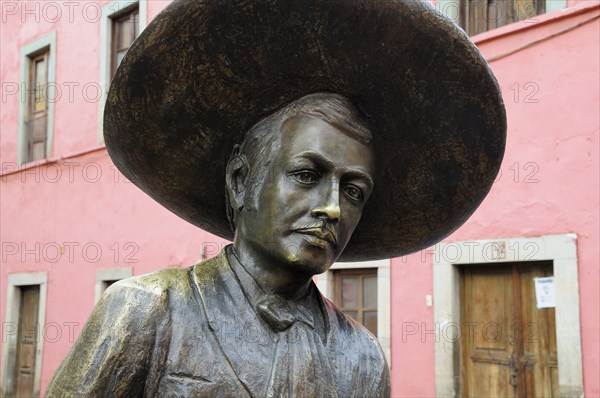 Mexico, Bajio, Guanajuato, Bronze statue of Charro singer Jorge Negrete with pink painted building facade behind. Photo : Nick Bonetti