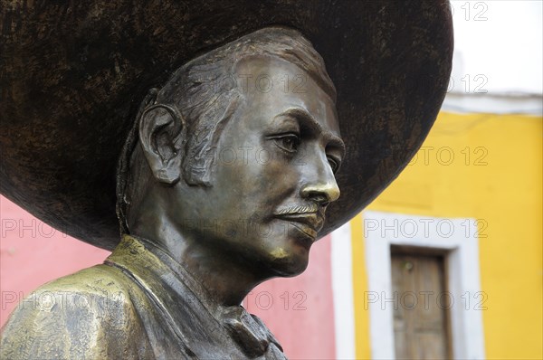 Mexico, Bajio, Guanajuato, Bronze statue of Charro singer Jorge Negrete with pink and yellow painted building facade behind. Photo : Nick Bonetti