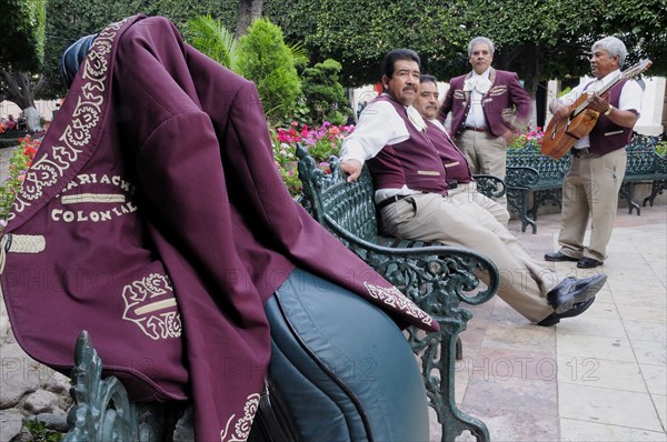 Mexico, Bajio, Guanajuato, Jardin de la Union Mariachi group taking a rest from playing purple jacket hung over music case in foreground.. Photo : Nick Bonetti