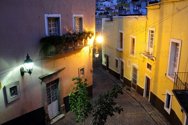 Mexico, Bajio, Guanajuato, Elevated view over street corner at night with painted building facades balconies and illuminated street lights. Photo : Nick Bonetti