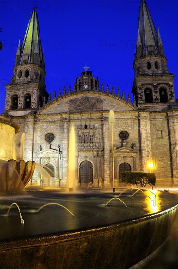 Mexico, Jalisco, Guadalajara, Fountain in foreground of cathedral exterior facade and bell towers at night in Plaza Guadalajara. Photo : Nick Bonetti