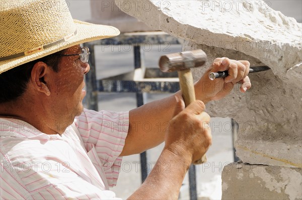 Mexico, Jalisco, Guadalajara, Plaza de la Liberacion Sculptor working stone with hammer and chisel. Photo : Nick Bonetti