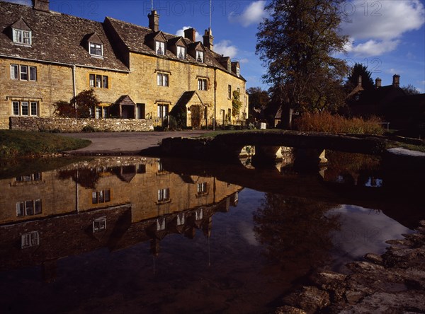 England, Gloucestershire, Cotswolds, Lower Slaughter. Village houses reflected in the River Eye. Photo : Bryan Pickering