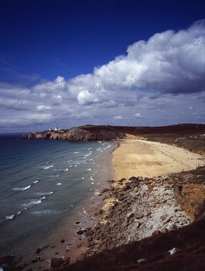 France, Bretagne, Crozon Peninsula, South west facing beach and Pointe du Toulinguet with rocky coastline and lighthouse on clifftop in distance. Photo : Bryan Pickering