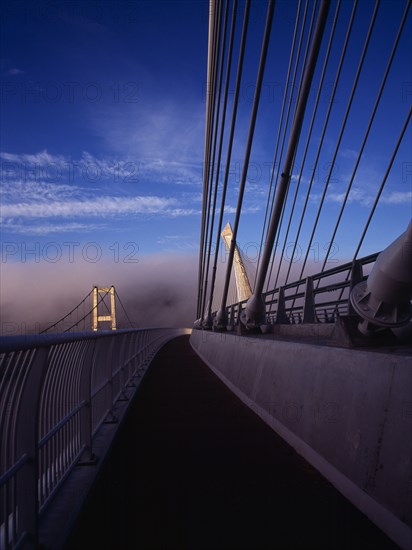 France, Bretagne, Finistere, Ile de Crozon. View of the old and new Pont de Terenez suspension bridges over the River Aulne from the east side of the new footway in early morning fog.. Photo : Bryan Pickering