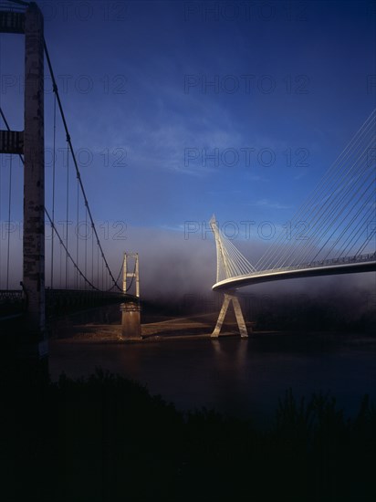 France, Bretagne, Finistere, Ile de Crozon. View of both old and new Pont de Terenez suspension bridges from north bank of the River Aulne in early morning fog. Photo : Bryan Pickering