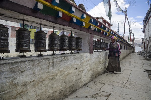 Nepal, Upper Mustang, Kagbeni, Woman prays using prayer wheels. Photo : Sergey Orlov