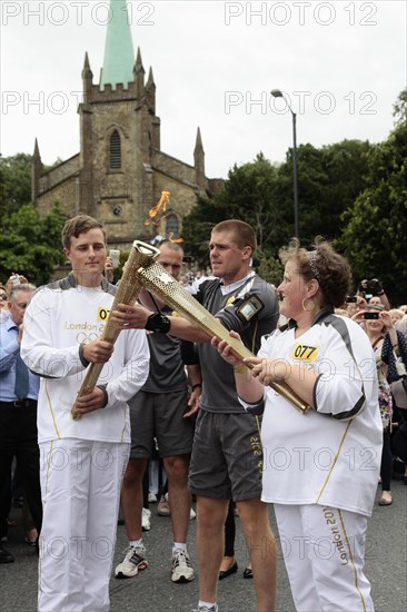 England, Kent, Tunbridge Wells, Olympic Torch relay runners handing over torch by exchanging the flame. Photo : Sean Aidan