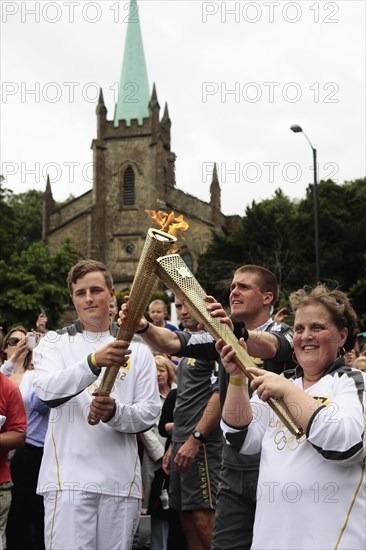 England, Kent, Tunbridge Wells, Olympic Torch relay runners handing over torch by exchanging the flame. Photo : Sean Aidan