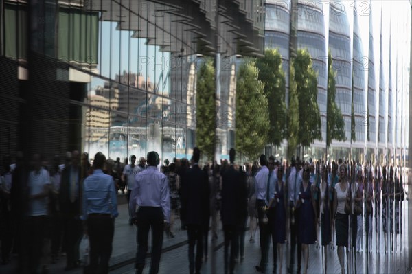 England, London, Southwark Office workers reflected in glass building next to City Hall. Photo : Sean Aidan