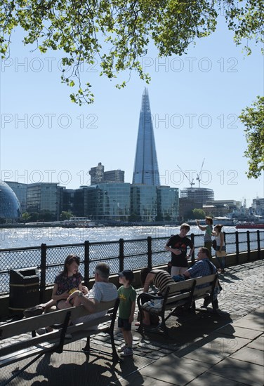 England, London, People relaxing on the North Bank of the river Thames with the Shard visible behind. Photo : Paul Tomlins