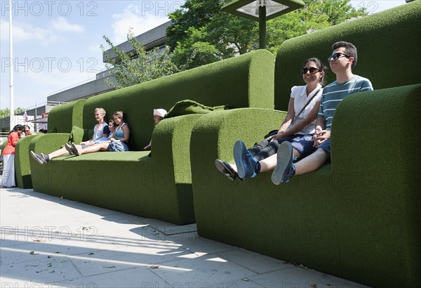 Tourists relax in giant green sofas on the South Bank of the river Thames, London England