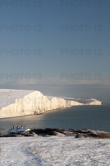 England, East Sussex, Seven Sisters, Snow covered coastline from Birling gap showing the Coastguard cottages in the foreground and Belle Tout lighthouse in the distance.. Photo : Bob Battersby