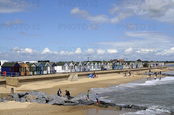 England, Suffolk, Southwold, Beach Huts near the pier with Sea Defences and Holidaymakers. Photo : Bob Battersby