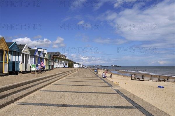 England, Suffolk, Southwold, Beach Huts near the pier with Sea Defences and Holidaymakers. Photo : Bob Battersby