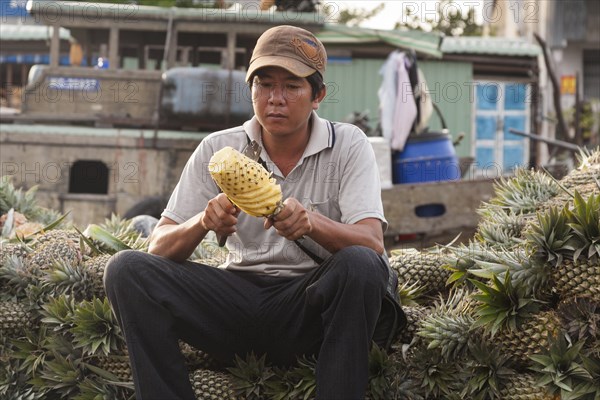Vietnam, Mekong Delta, Man cutting a pineapple in the floating market at Cai Rang near Can Tho. Photo : Mel Longhurst
